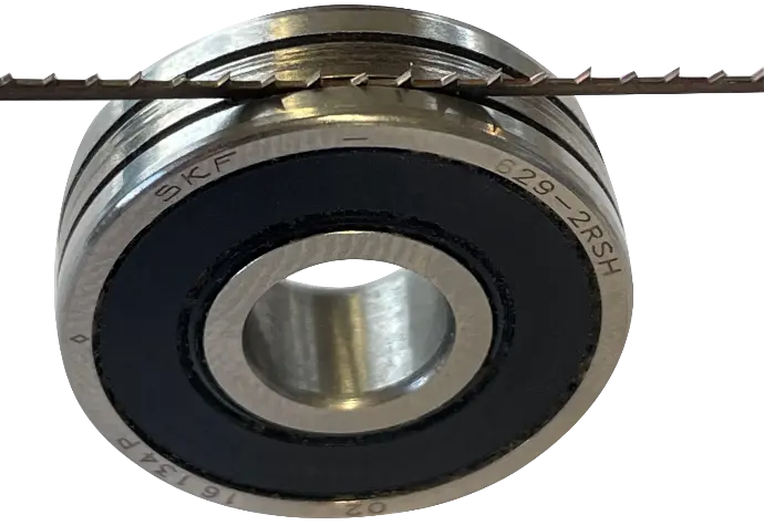 Manufacturer illustration of a scroll bandsaw blade seated in a grooved guide bearing; representative guide principle, not a size-specific photo